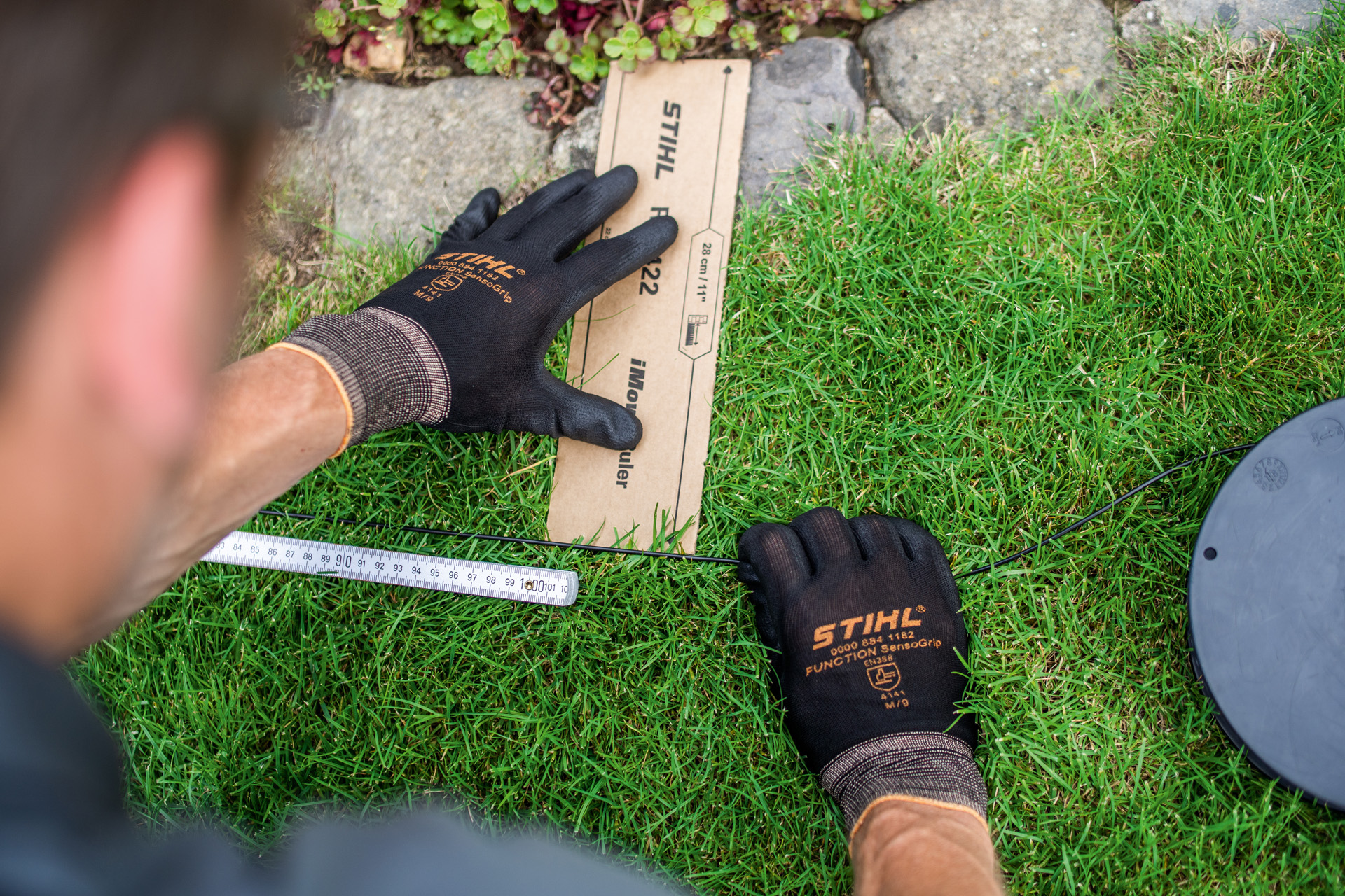 STIHL dealer installeert begrenzingsdraad voor de STIHL iMOW robotmaaier aan een graskant